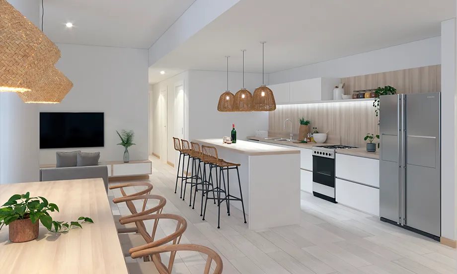 render de la cocina con una vista del living en dónde se ve una isla con tres banquetas, tres luces colgantes y una cocina equipada con heladera, horno, hornallas y una mesada. al extremo izquierdo se ve una televisión con una mesa grande con 4 sillas de cada lado